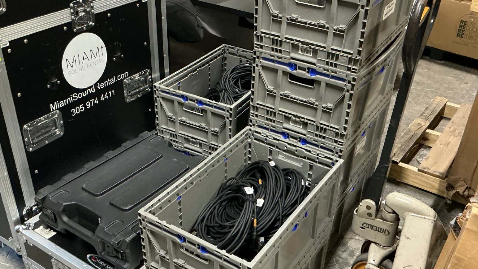 Coiled XLR audio cables organized in Miami Sound Rental inventory bins