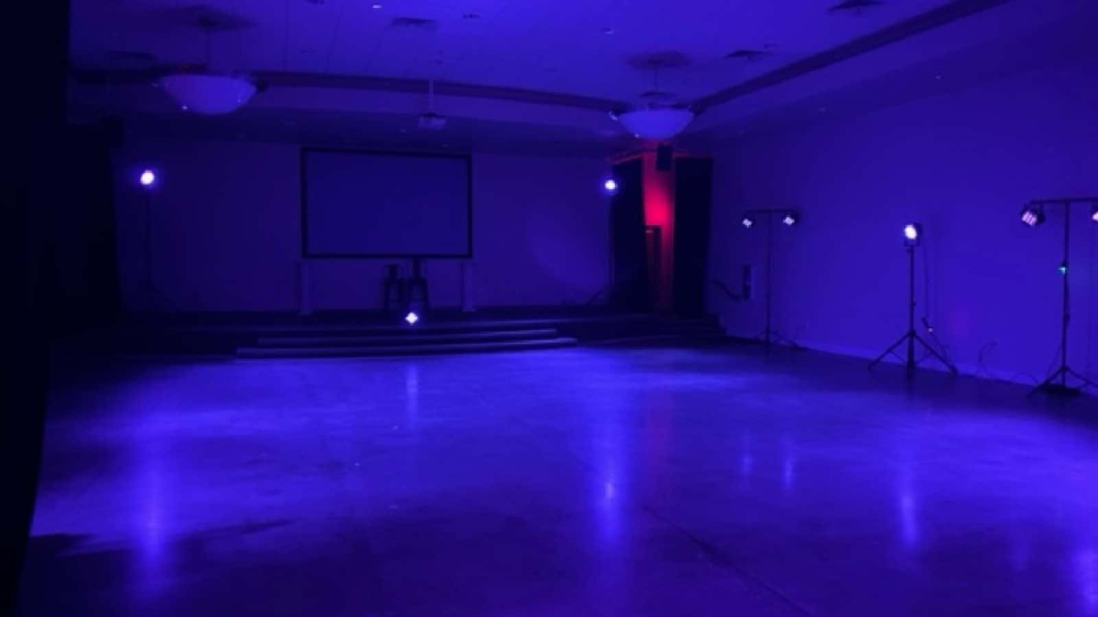 UV-capable wash fixtures casting violet light across an indoor event room