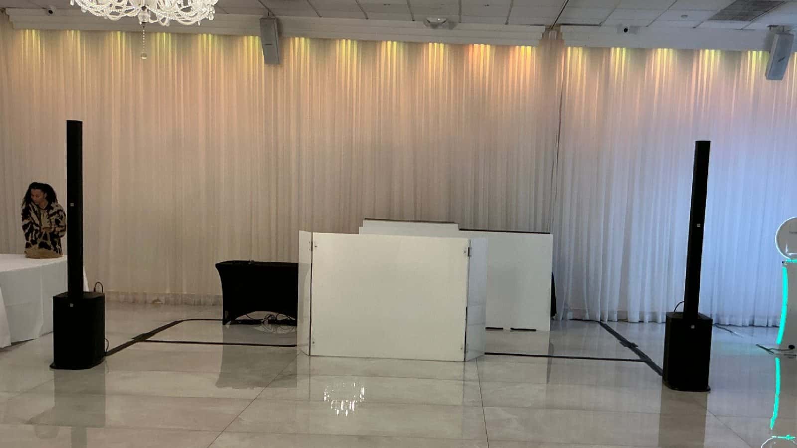 White acrylic DJ facade installed with speakers in an indoor event venue