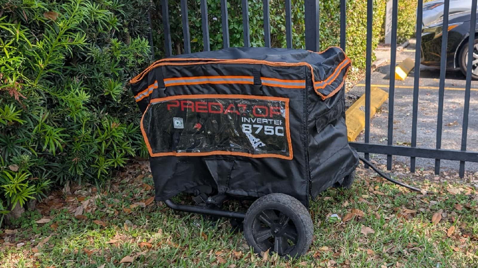 Portable inverter generator positioned outdoors beneath a fitted protective cover