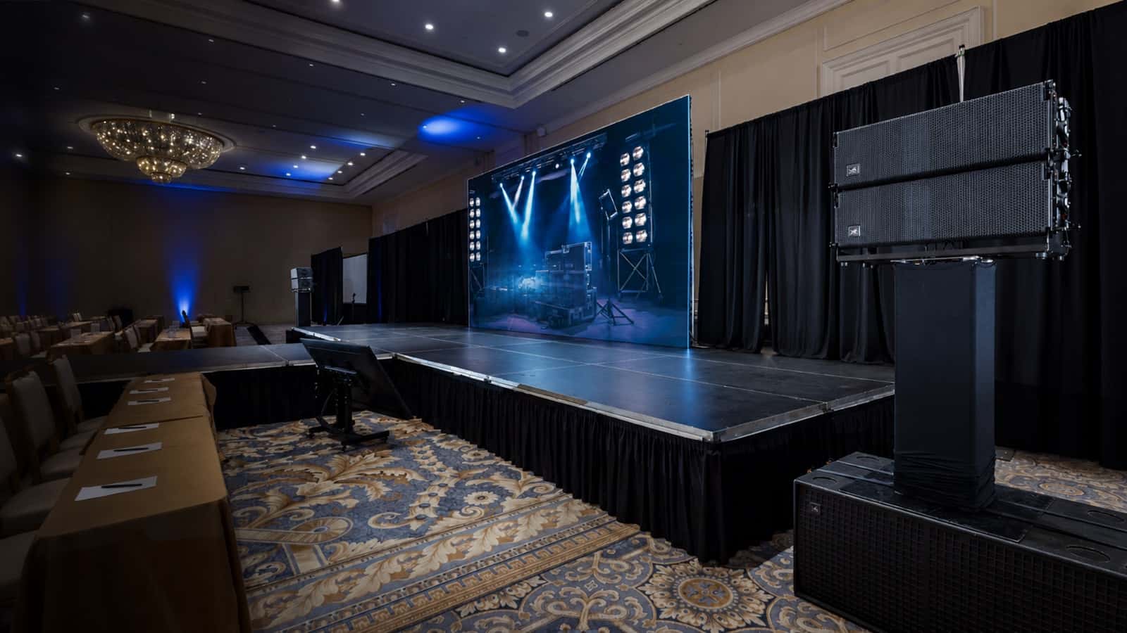 Line-array speaker stacks deployed beside a ballroom stage