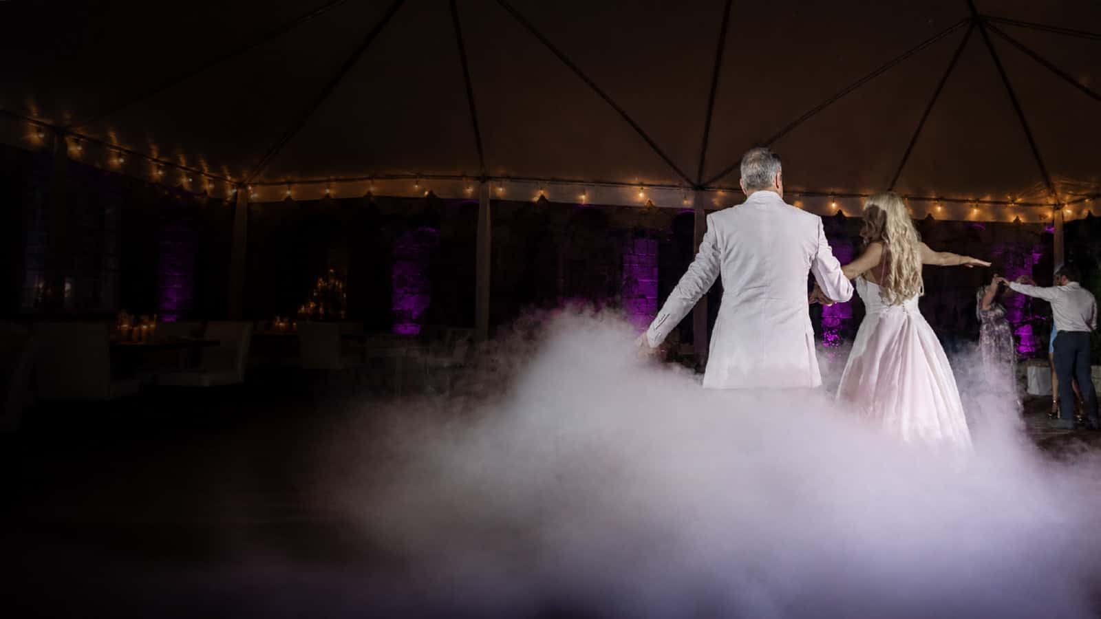 Couple dancing in low-lying fog under an event tent