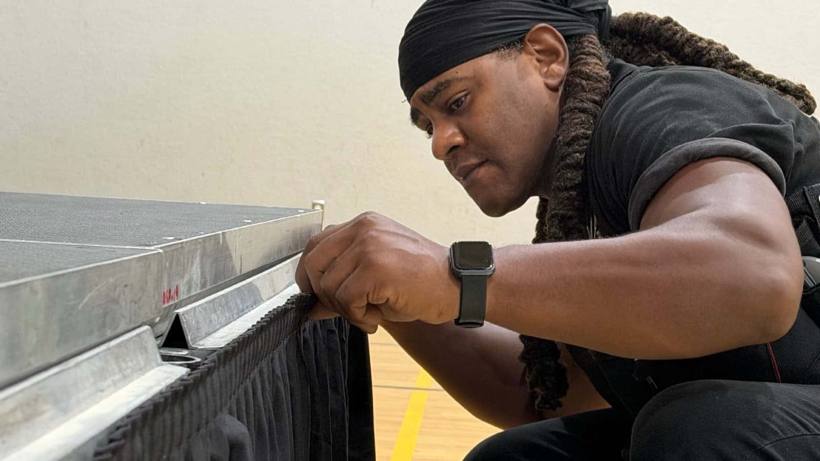 Technician attaching black skirting to the edge of a portable stage