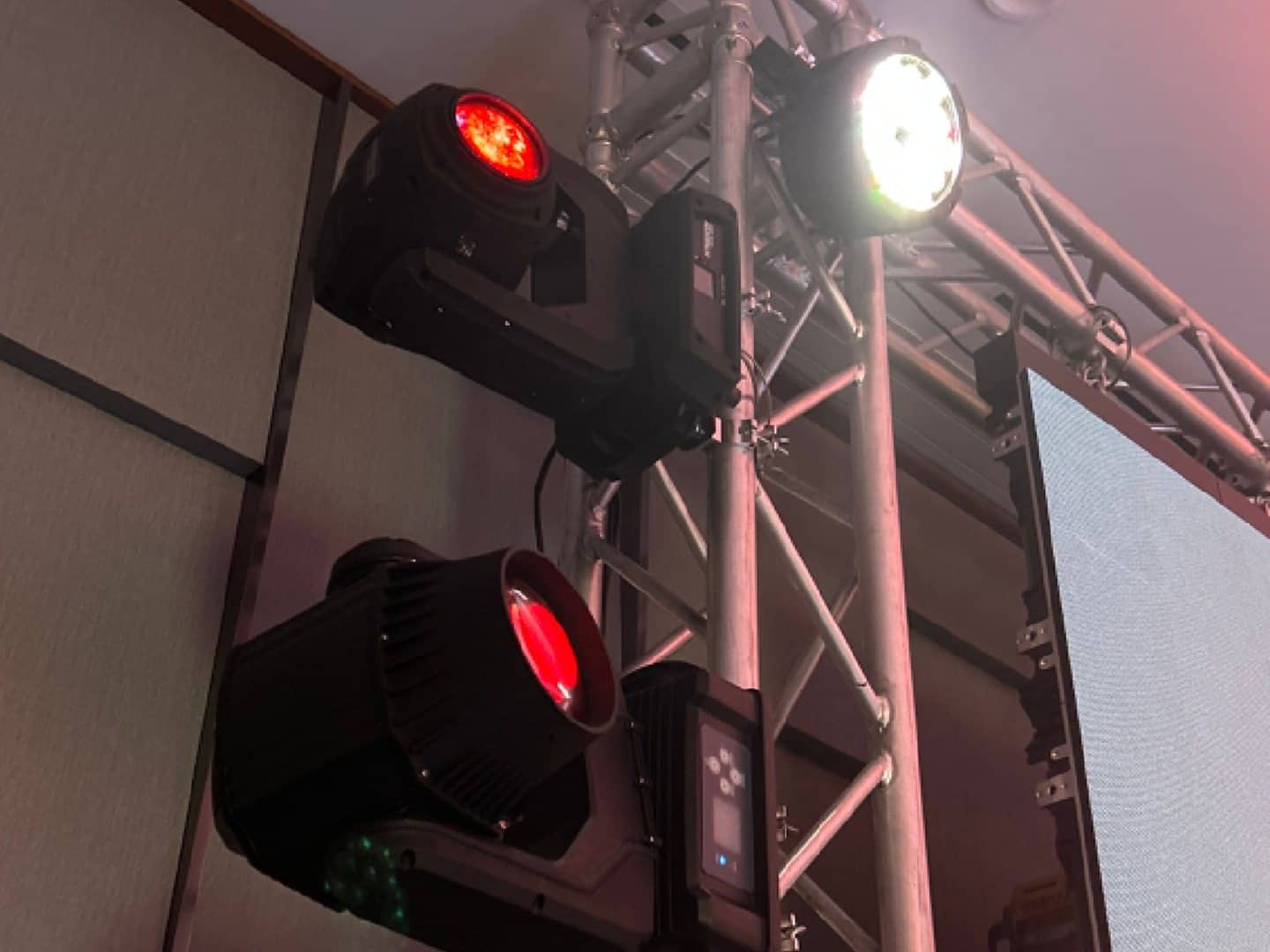 Moving-head fixture mounted beside other lighting on an event truss