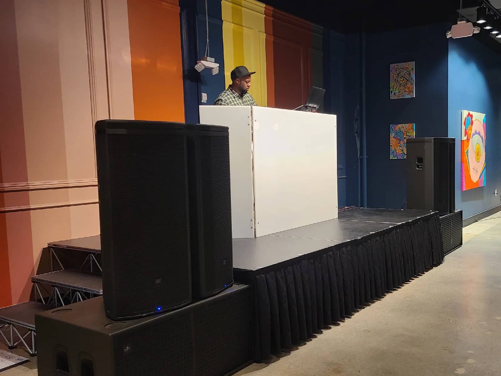 DJ setup flanked by professional powered speakers and subwoofers