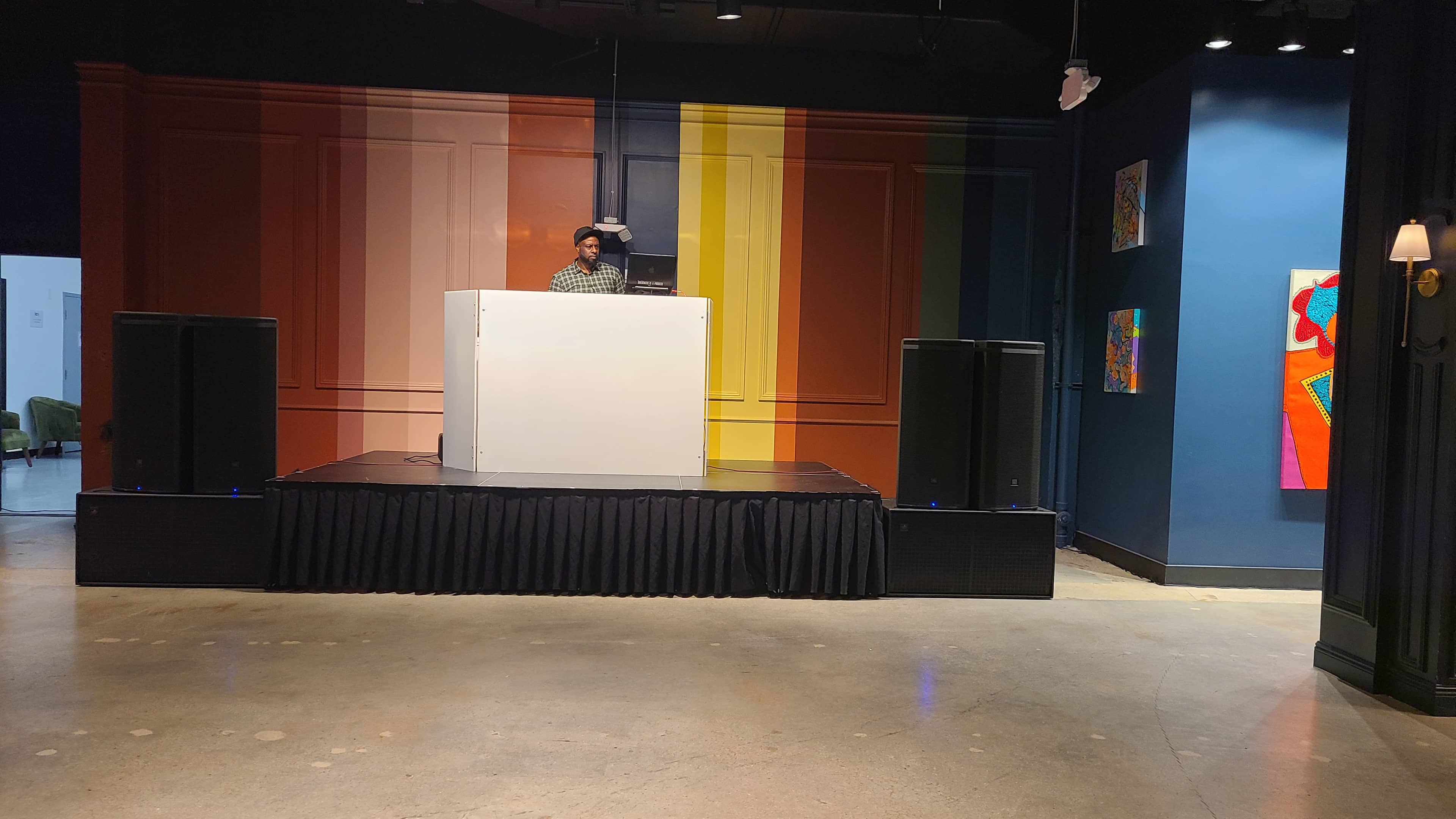 Four professional powered speakers positioned around a DJ stage