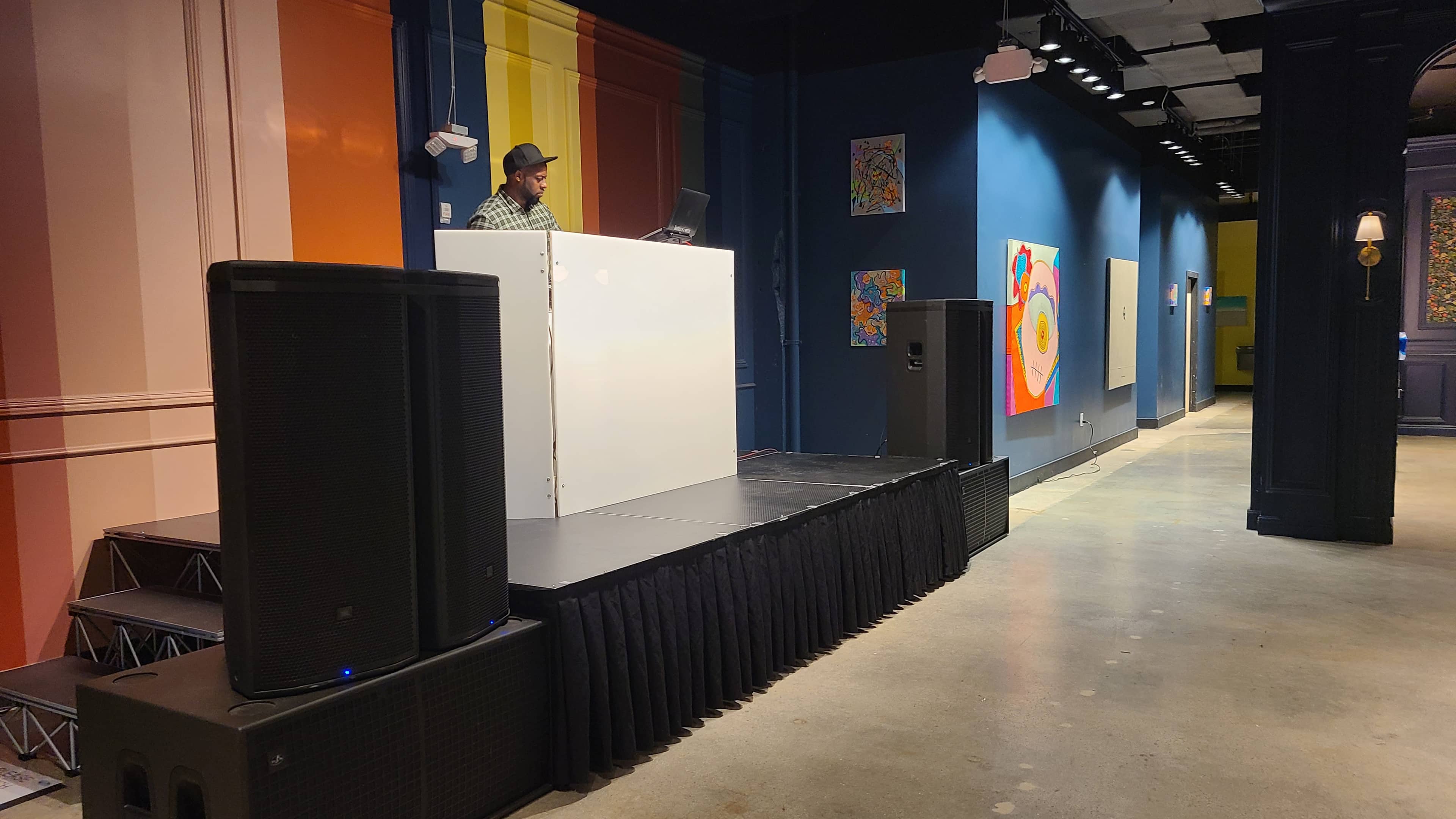Professional powered speakers and subwoofers arranged around a DJ stage