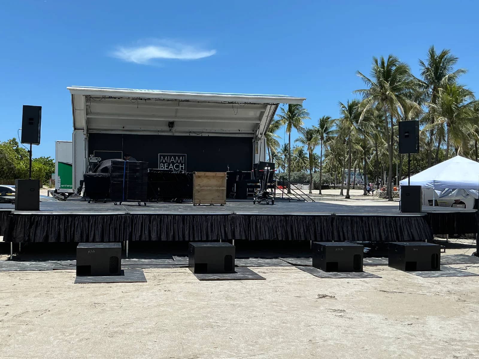 Portable modular outdoor stage assembled on Miami Beach with black skirting and sound equipment