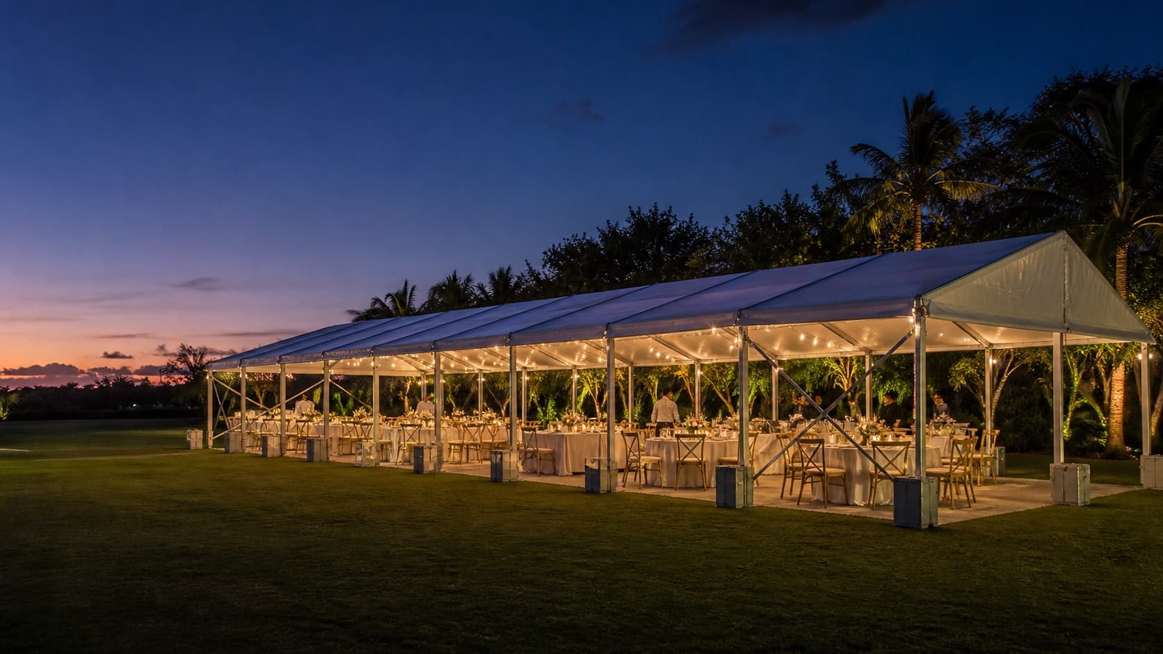 Long white frame tent prepared for an outdoor evening reception in Miami