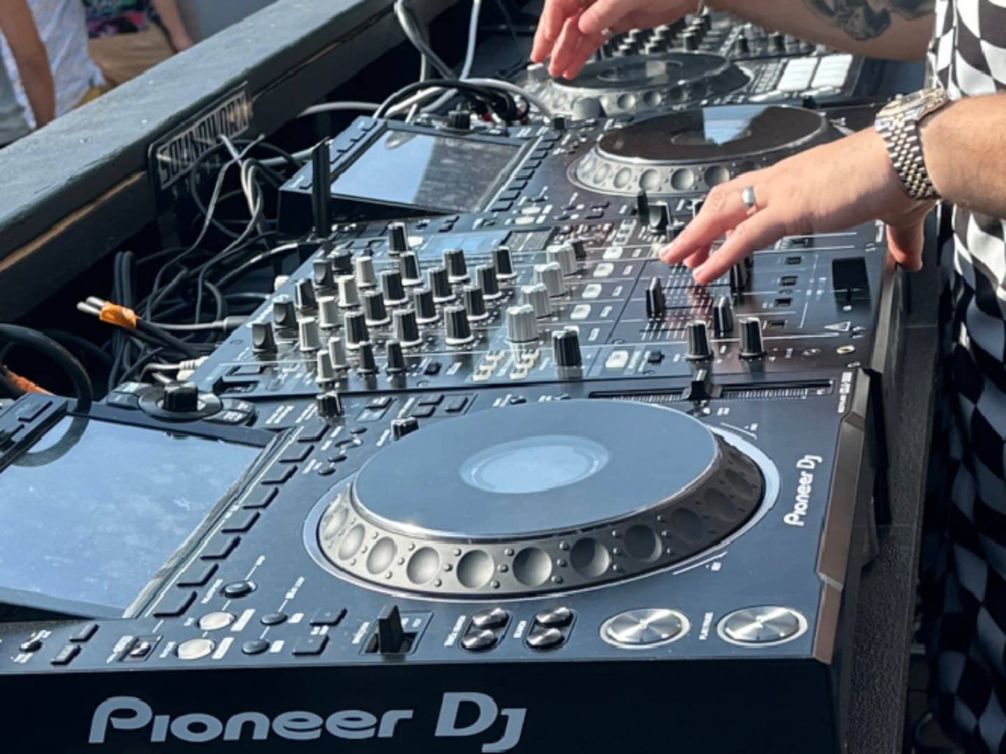 Hands operating CDJ decks and mixer controls