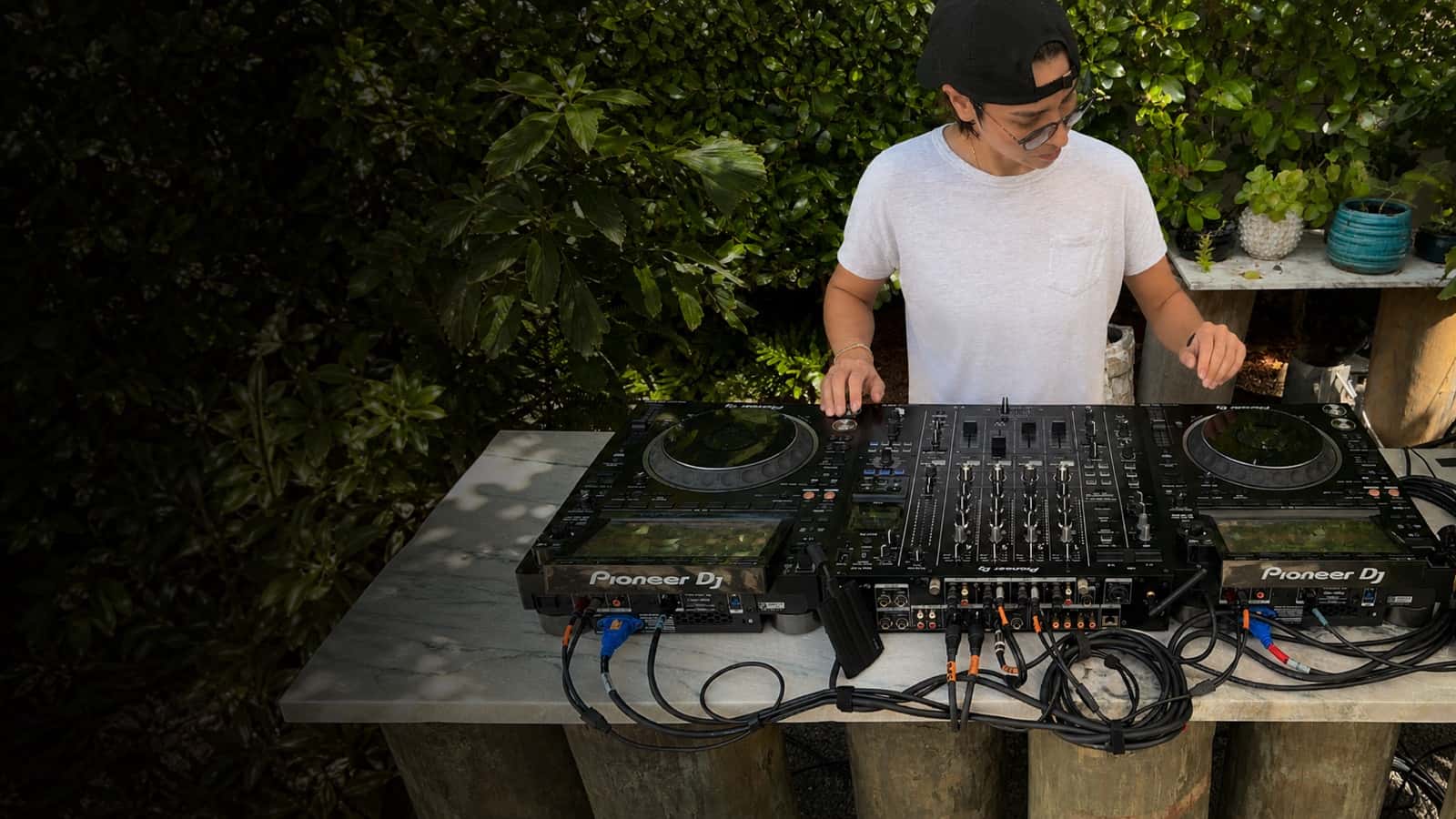 DJ operating two CDJs and a central mixer at an outdoor event