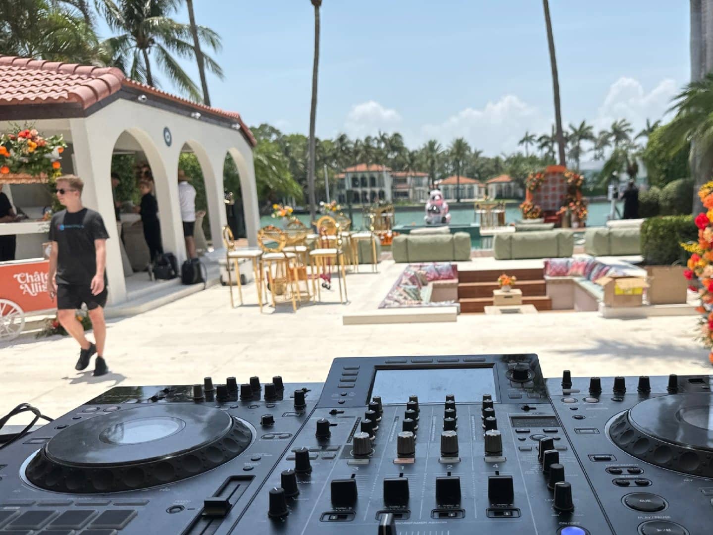 DJ controller in the foreground of an outdoor Miami event setup