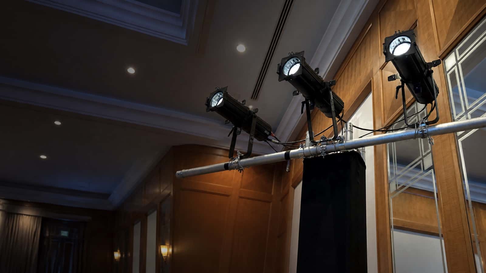 Three spotlights mounted on a crossbar in a ballroom