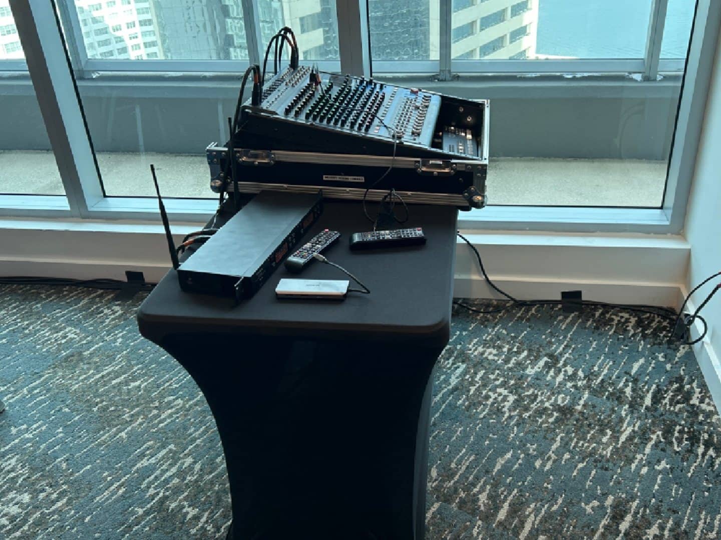 Black-covered four-foot table used beneath an event audio mixer