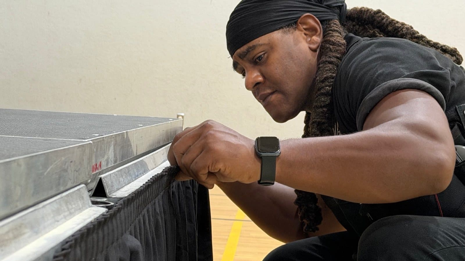 Technician attaching black skirting to the edge of a portable stage