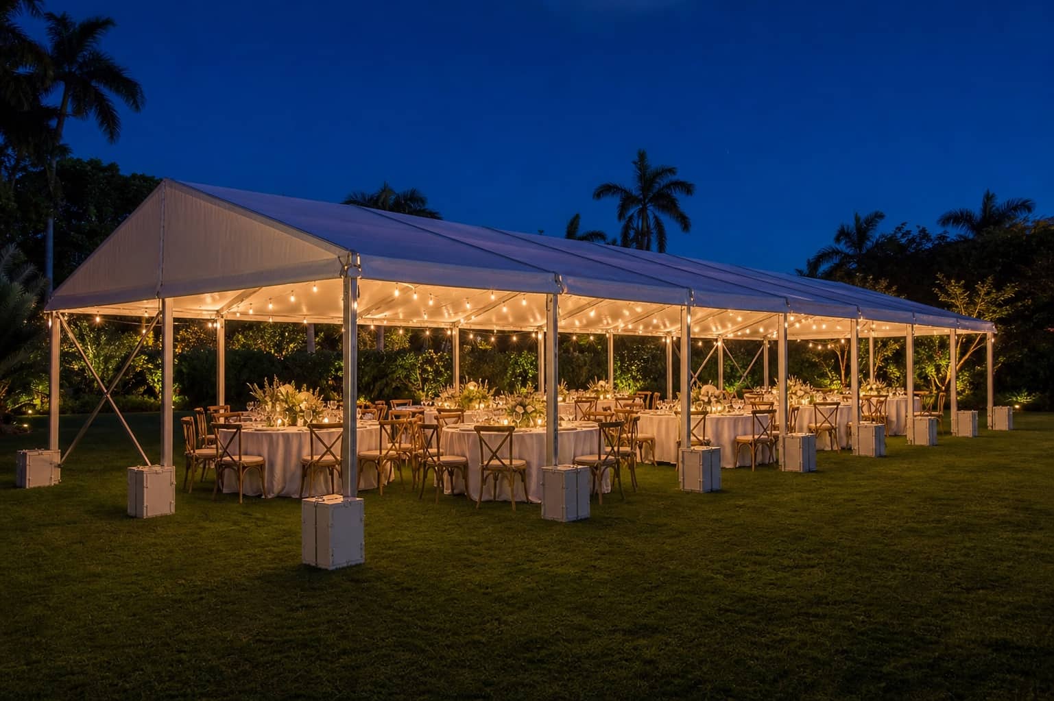 Professionally installed white frame party tent with ballast, dining tables and clear circulation on a South Florida lawn