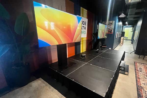 Flat-screen display on a stand beside a small presentation stage