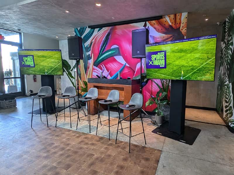 Two flat-screen TVs on stands supporting a sports watch party